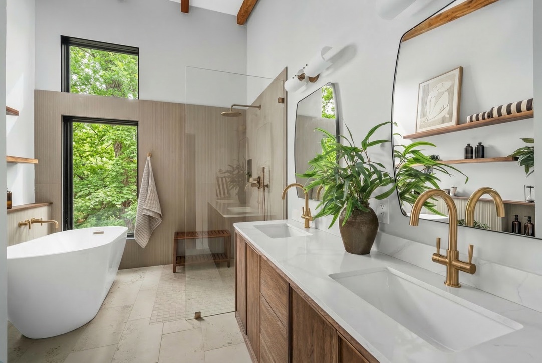 Primary bathroom with warm wood vanity and garden views