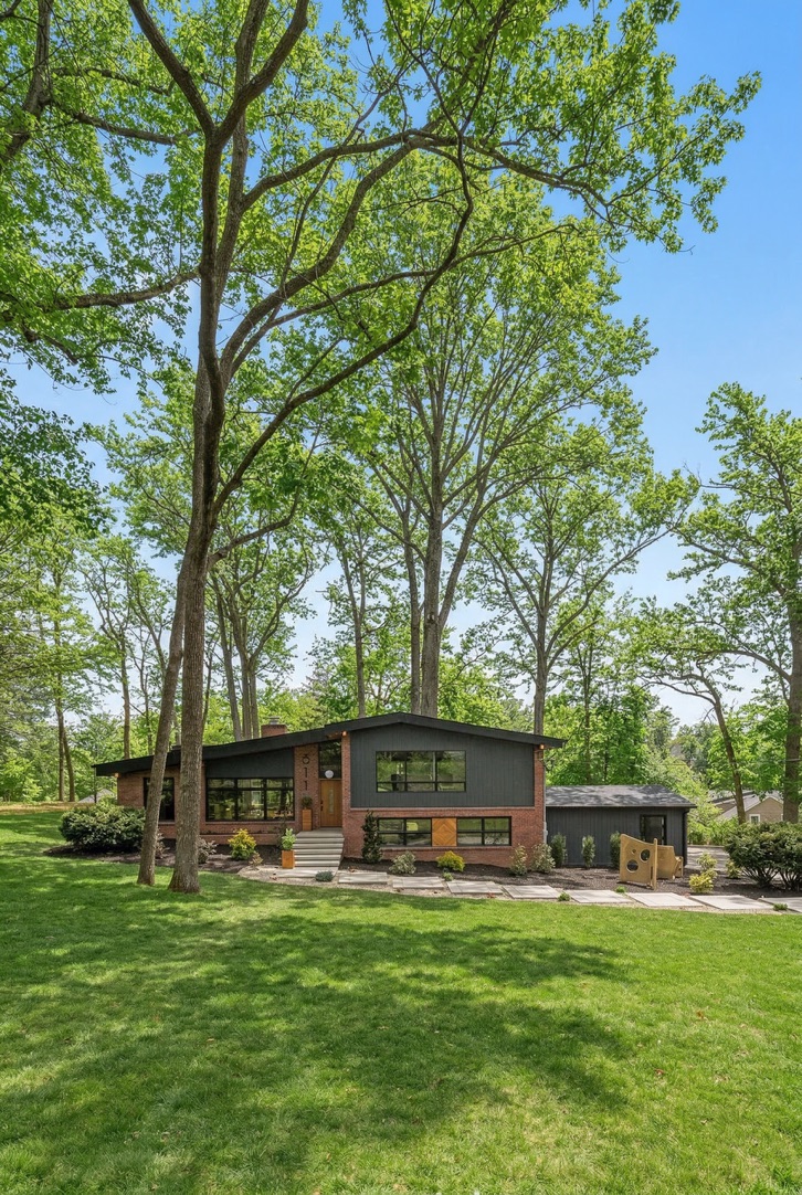 Wide view of the original mid-century home among mature trees