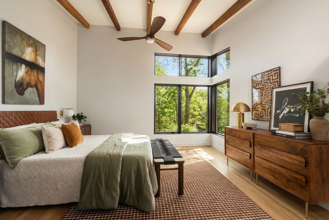 Primary bedroom with exposed beams and wooded views